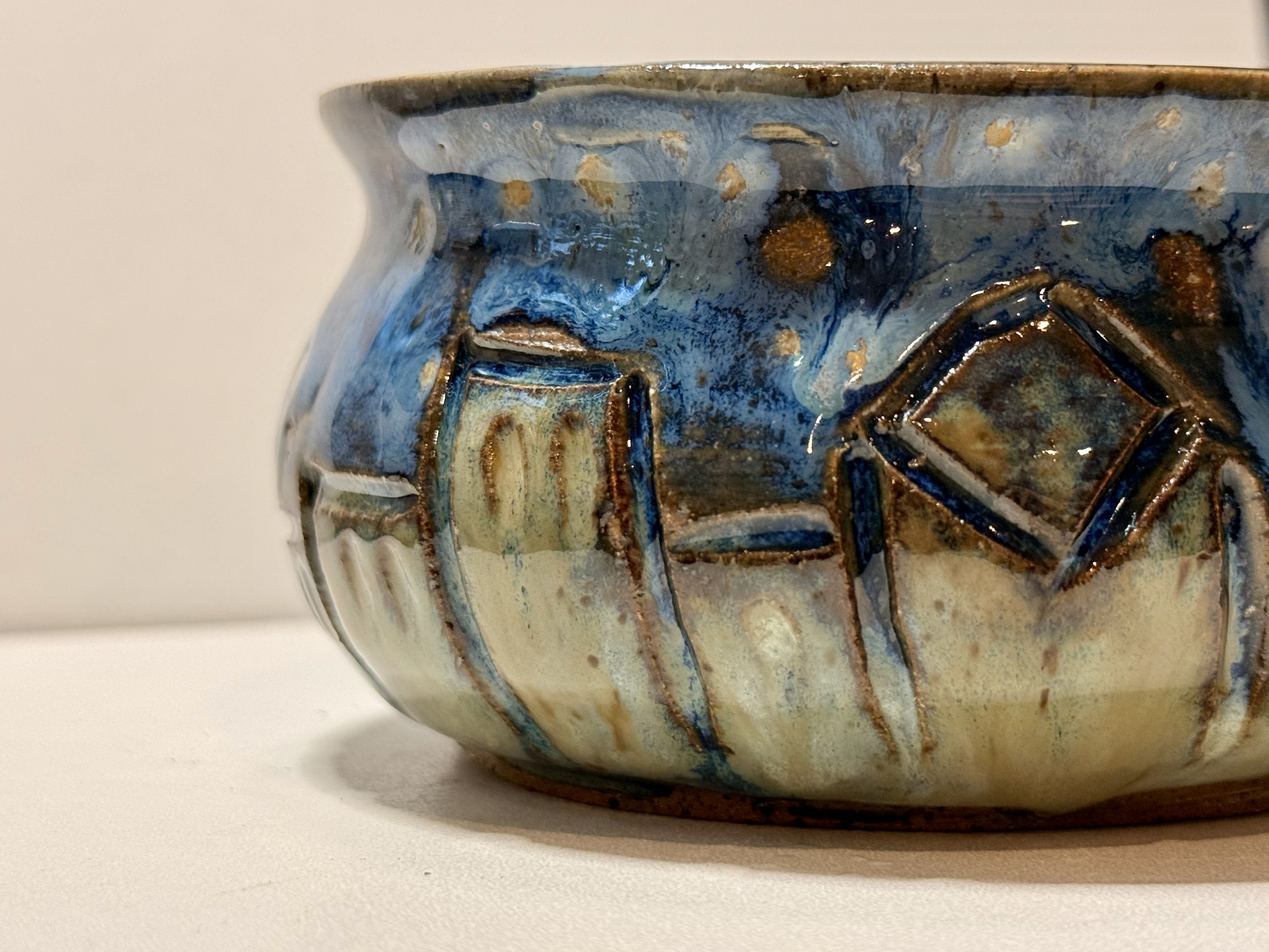 Blue glaze and house outlines on a rounded bowl.