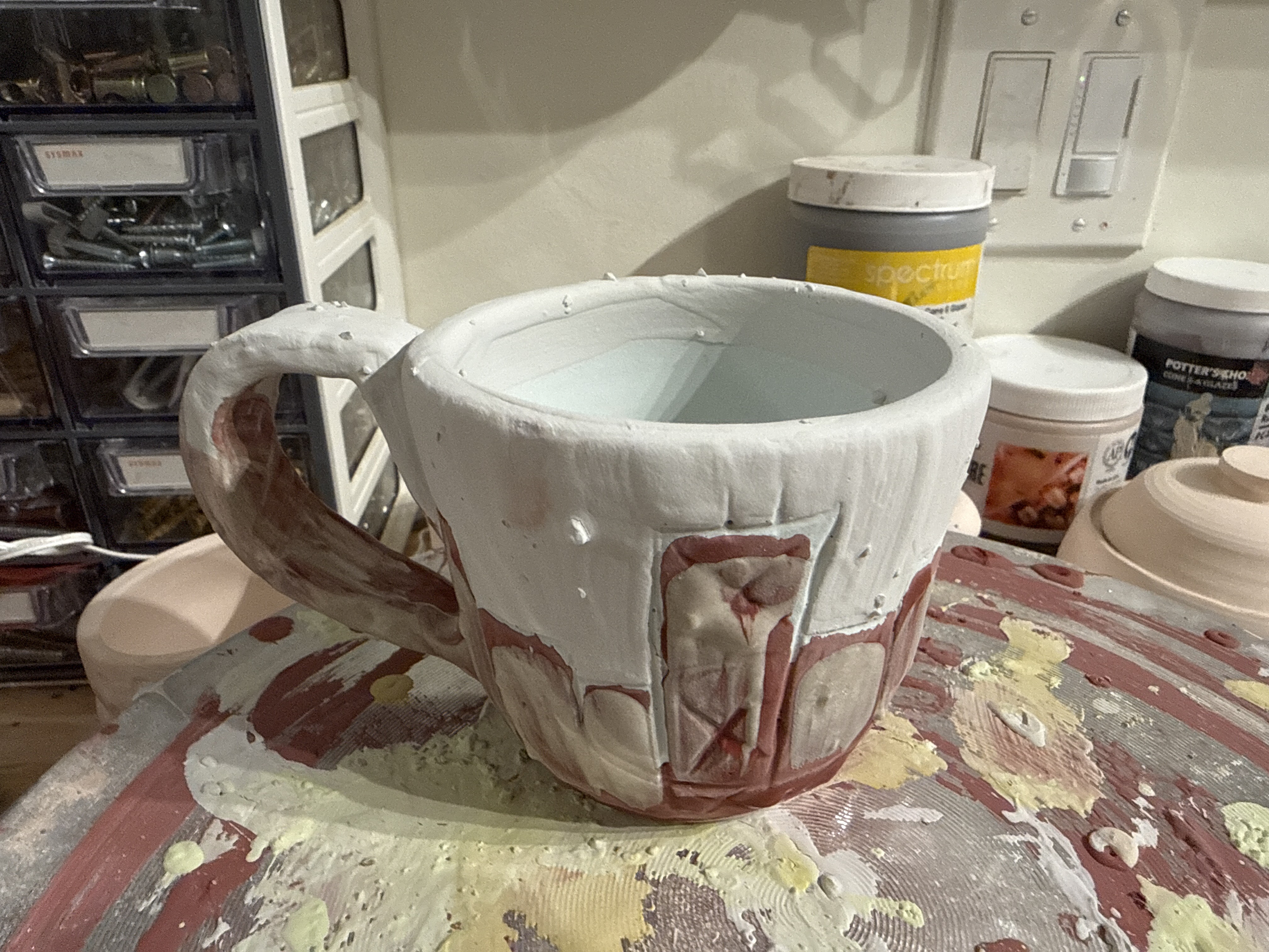 A mug during glazing, before firing.