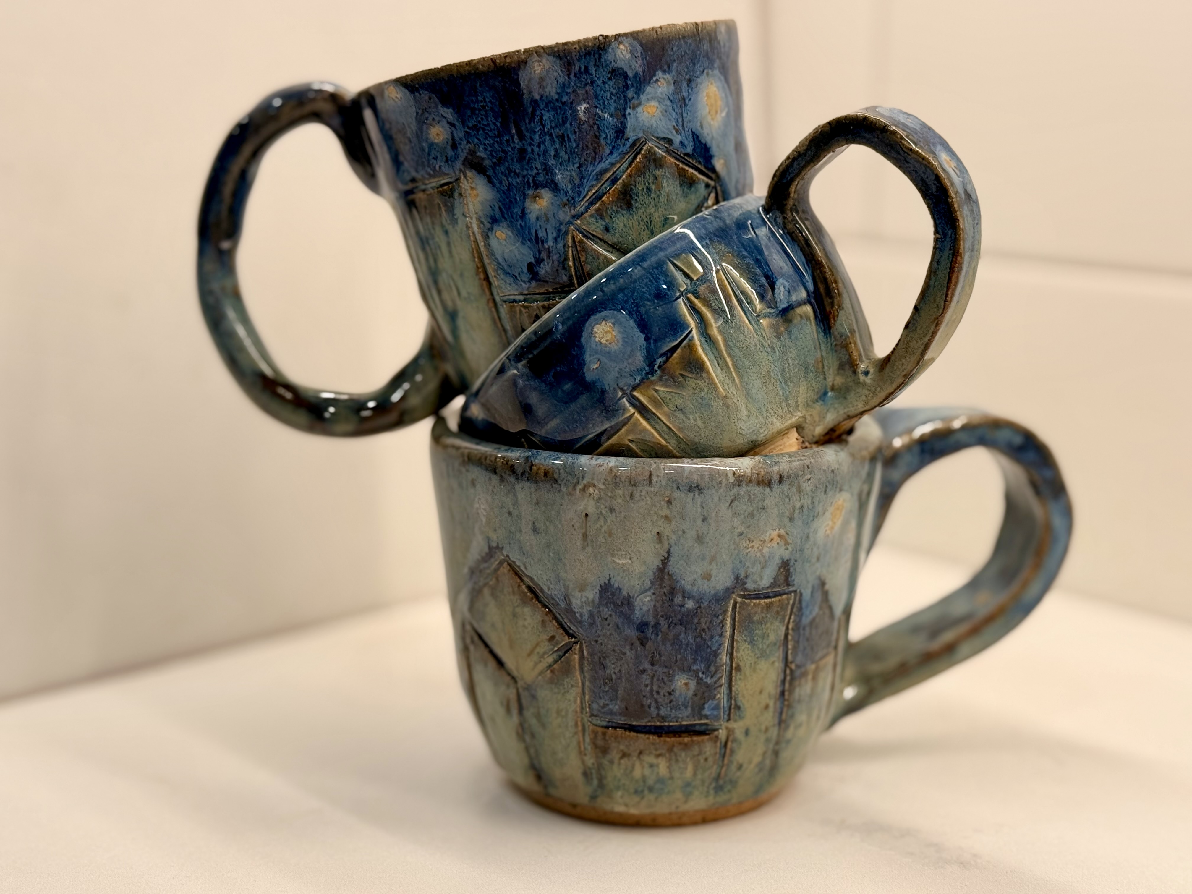 Three mugs with carved house designs.